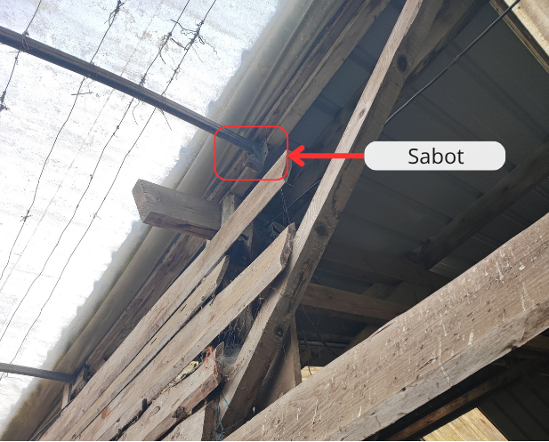 Photo annotée du sabot réalisant la jonction entre la demi-serre et la charpente de la grange.
